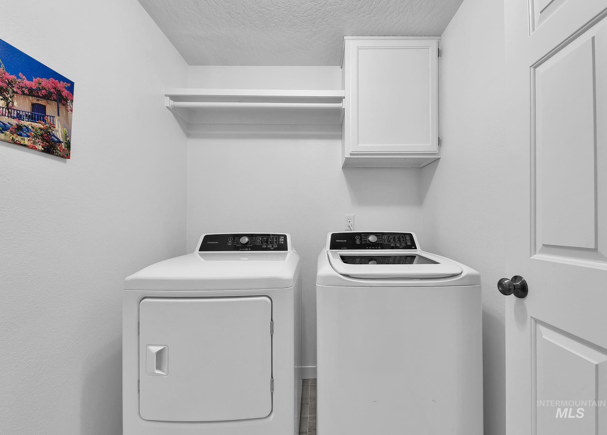 Laundry area with a textured ceiling, cabinet space, and independent washer and dryer