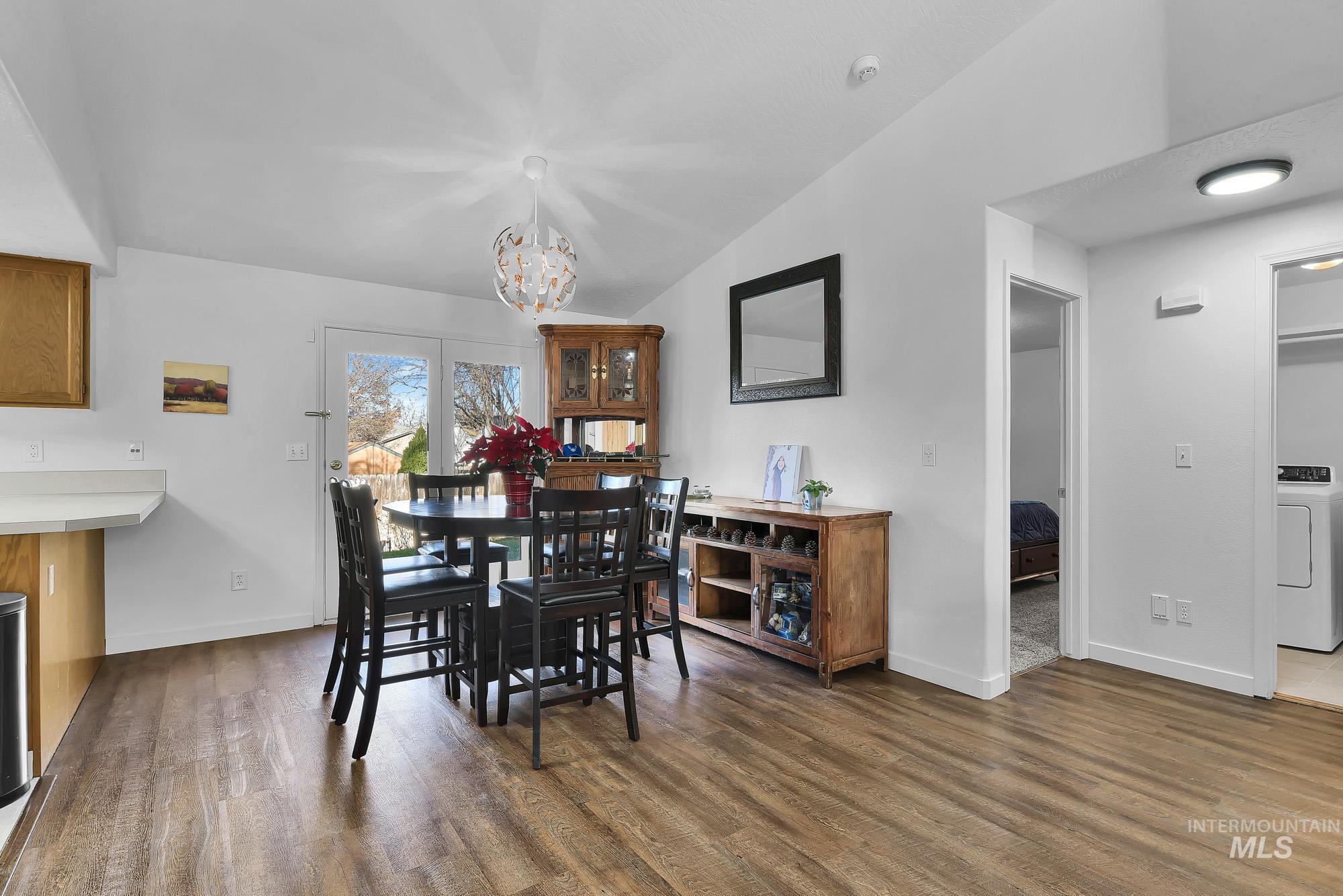 Dining area with lofted ceiling, washer / dryer, dark wood-style flooring, and a chandelier
