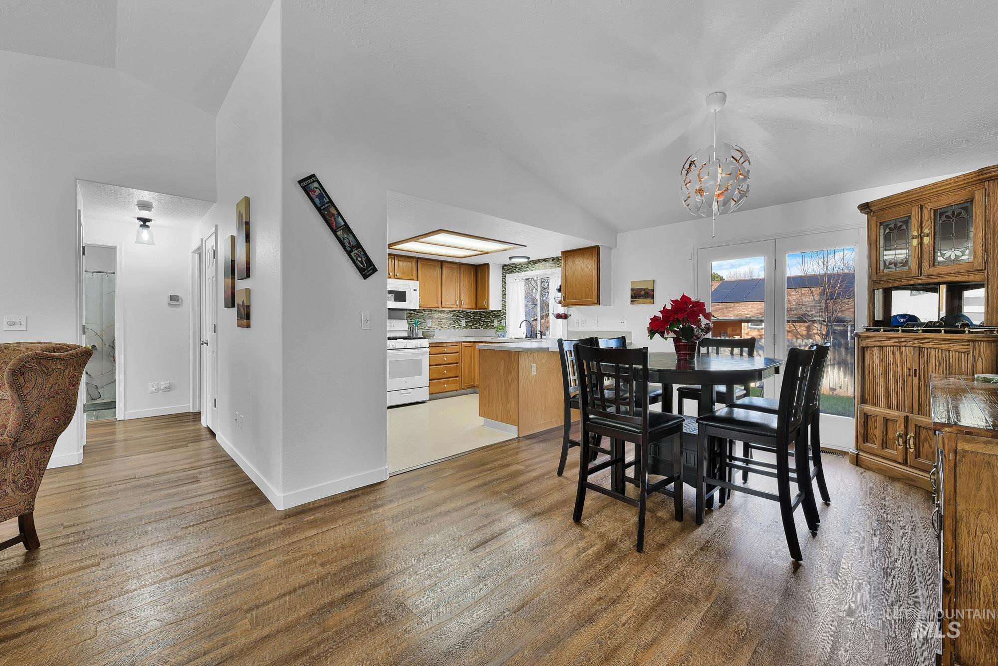 Dining area featuring vaulted ceiling, light wood-type flooring, and a chandelier
