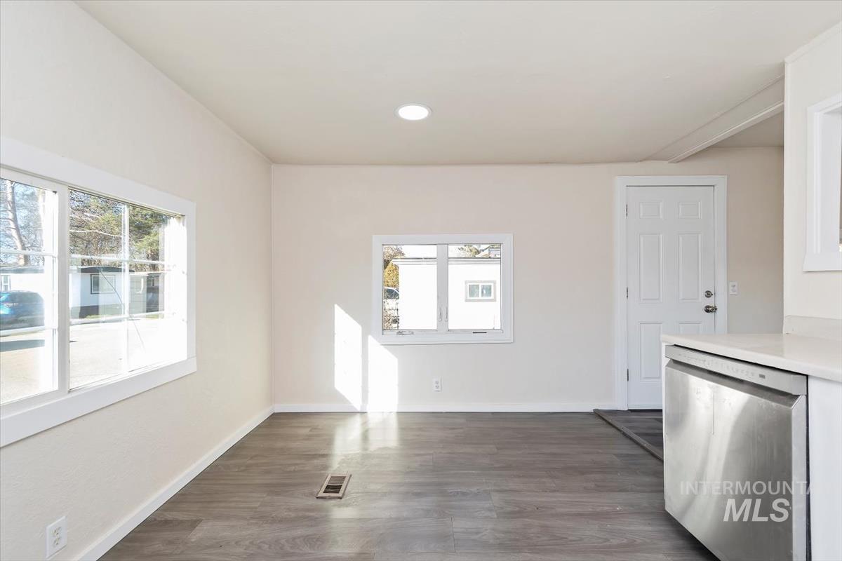 Kitchen with stainless steel dishwasher, dark wood-style flooring, recessed lighting, white cabinets, and light stone countertops
