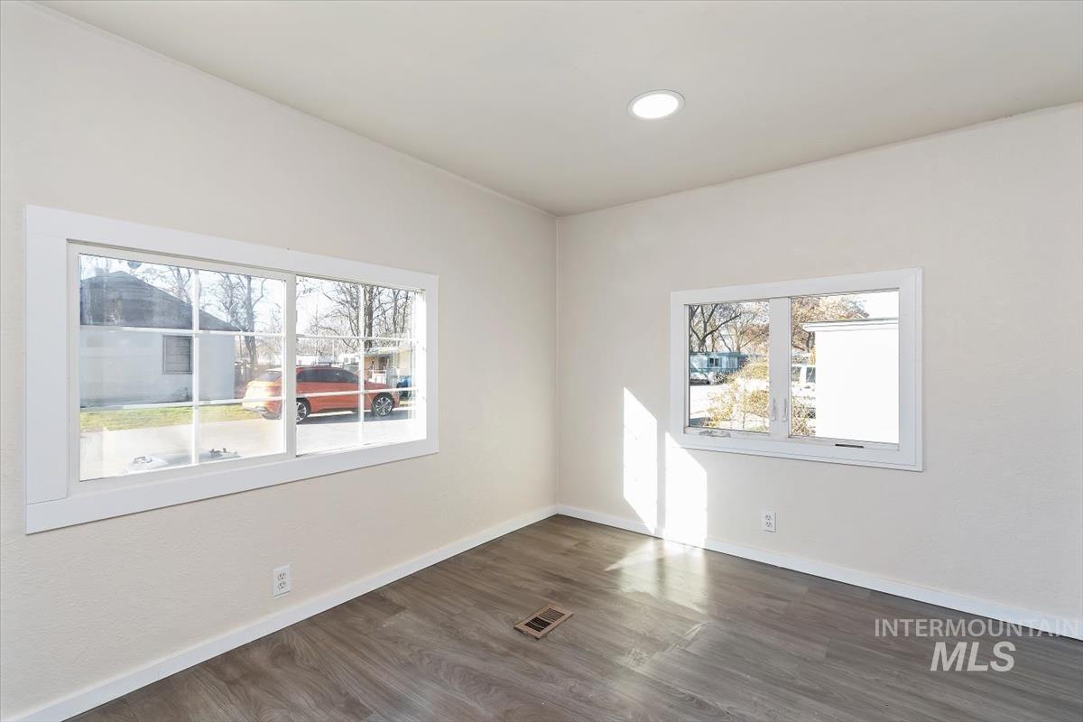 Empty room with dark wood-style floors and recessed lighting