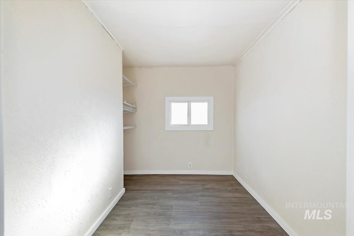 Empty room with dark wood-style flooring and baseboards