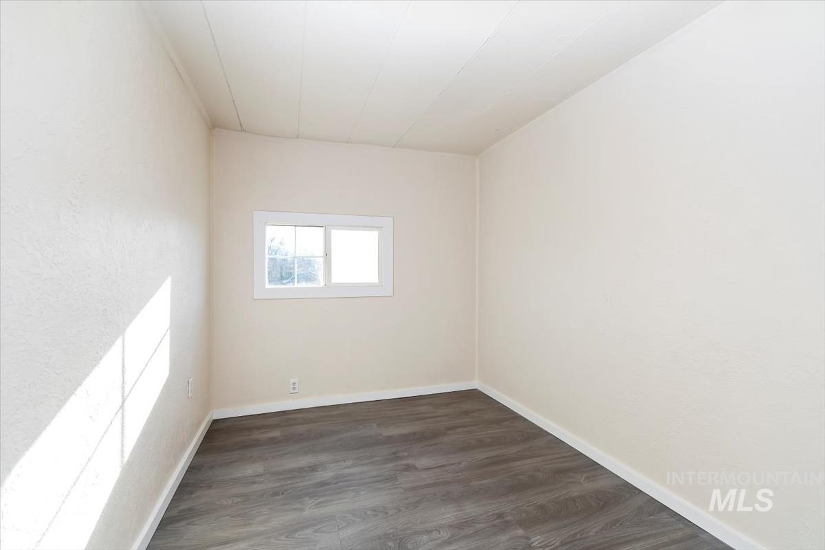 Unfurnished room with dark wood-style floors and baseboards