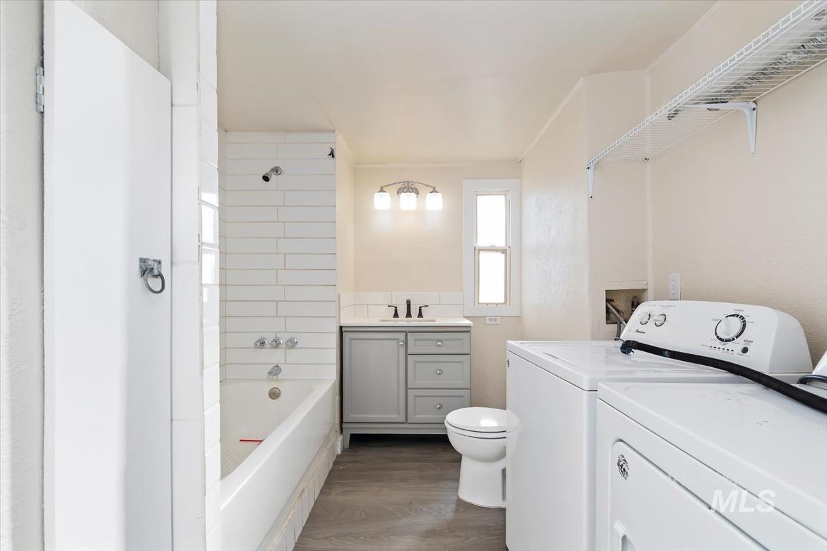 Bathroom featuring vanity, shower / washtub combination, dark wood-style floors, and washer and clothes dryer