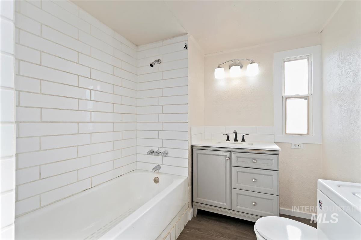 Bathroom featuring vanity, shower / bathtub combination, dark wood-style flooring, and washer / clothes dryer