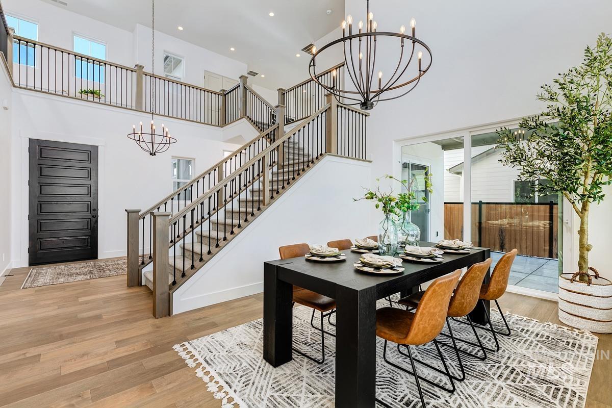 Dining room featuring a chandelier, light wood-style floors, recessed lighting, a high ceiling, and stairs