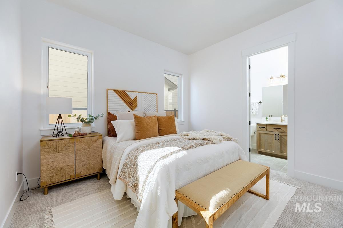 Bedroom featuring light carpet and ensuite bathroom