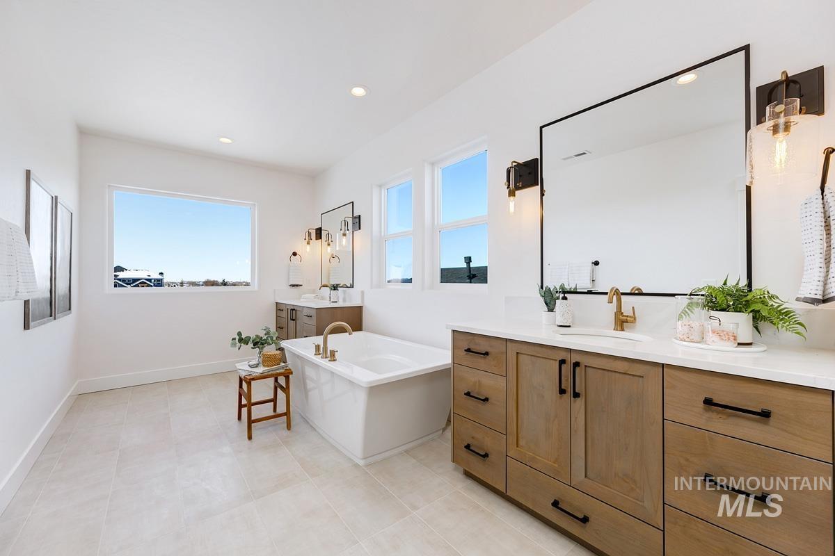 Full bath with two vanities, a freestanding bath, and recessed lighting