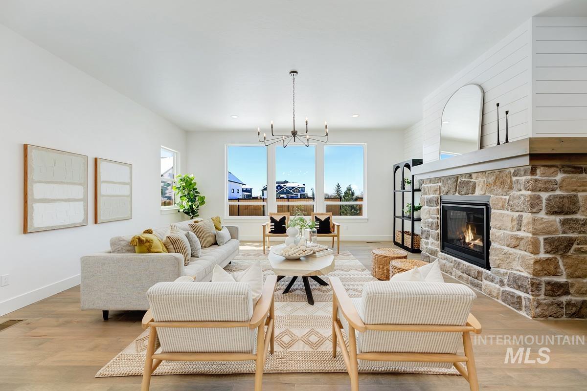 Living area with light wood-style floors, a fireplace, and a chandelier