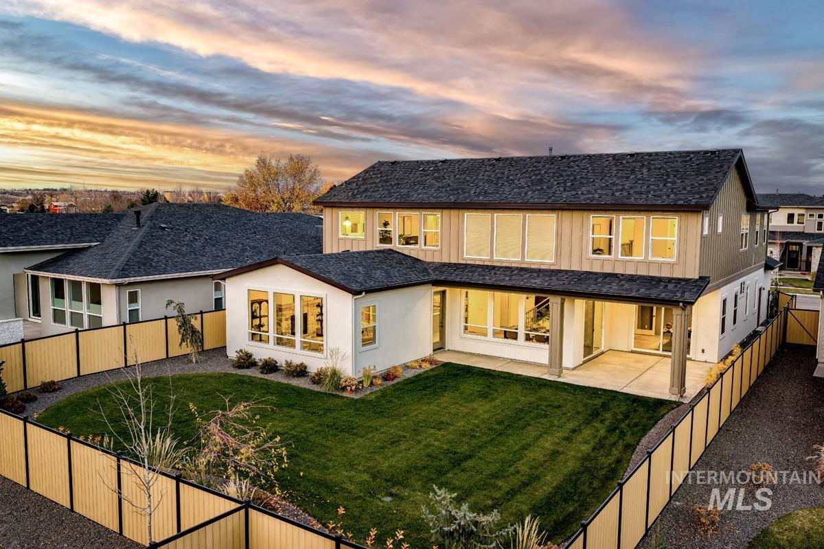 Back of property at dusk with a fenced backyard, a patio area, and stucco siding