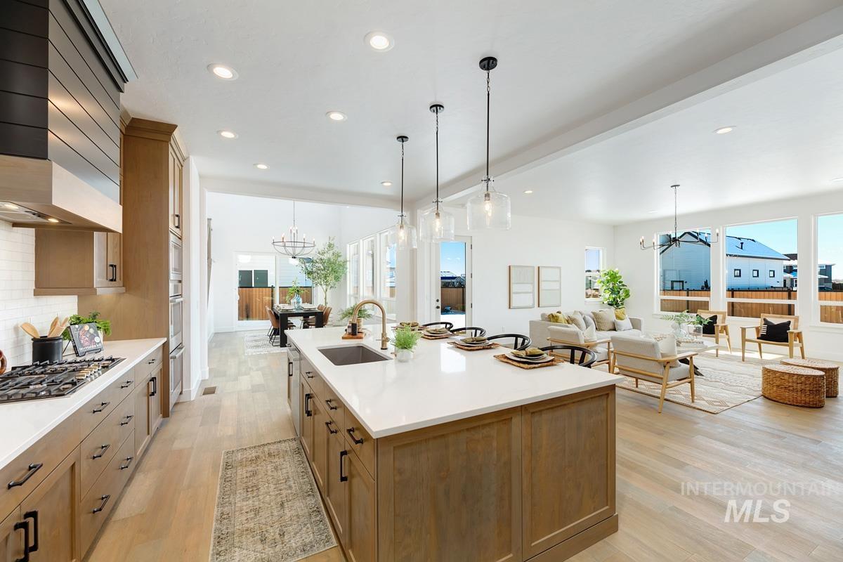 Kitchen with a chandelier, brown cabinetry, premium range hood, decorative light fixtures, and recessed lighting
