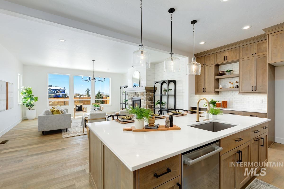 Kitchen featuring decorative backsplash, decorative light fixtures, open floor plan, light wood-style flooring, and light stone counters