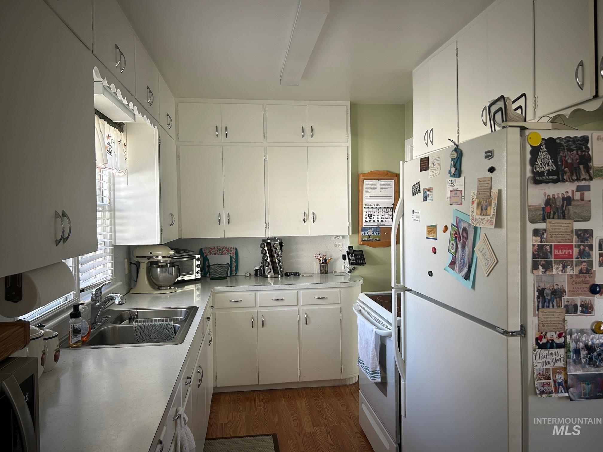 Kitchen with white appliances, light countertops, white cabinets, dark wood finished floors, and backsplash