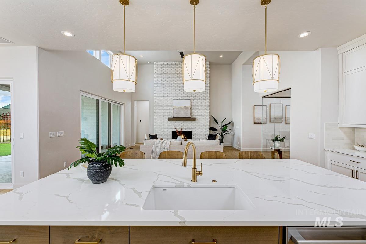 Kitchen with a center island with sink, light stone counters, decorative light fixtures, open floor plan, and a fireplace