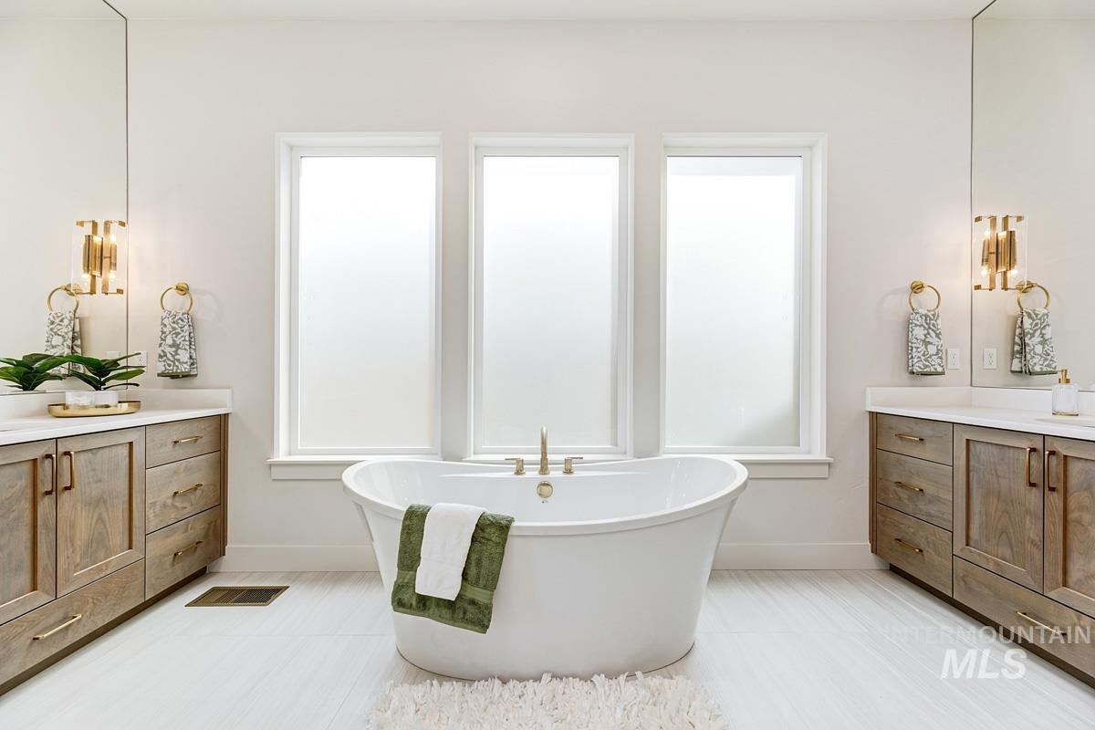Full bathroom with vanity, a soaking tub, and plenty of natural light