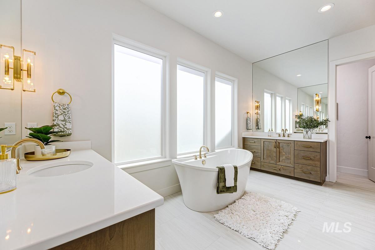 Full bathroom with two vanities, a freestanding tub, recessed lighting, and a chandelier