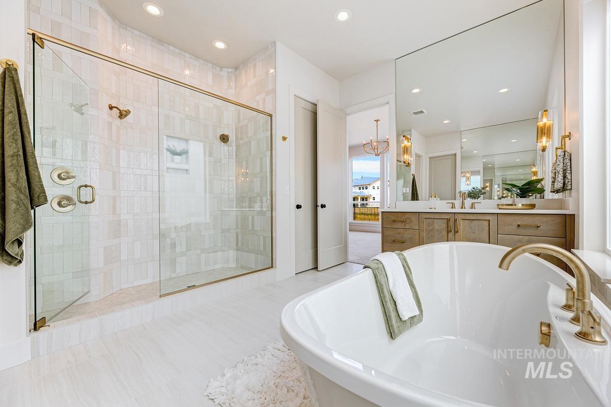 Full bath with a soaking tub, vanity, a chandelier, a shower stall, and recessed lighting