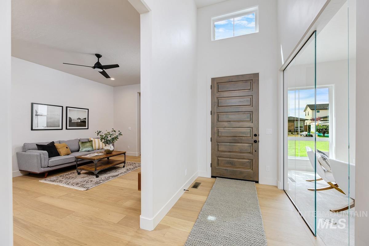 Foyer entrance featuring ceiling fan, light wood-type flooring, and a towering ceiling