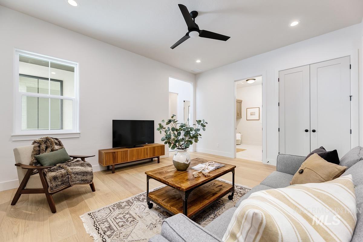 Living room with light wood-type flooring, a ceiling fan, and recessed lighting