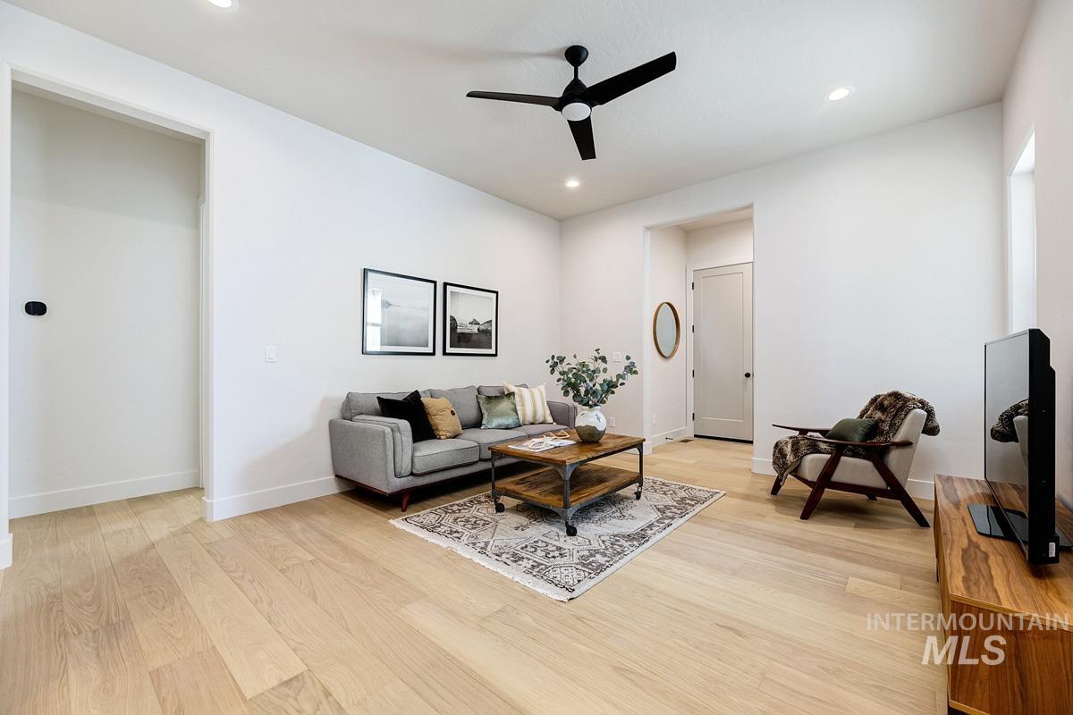 Living room with light wood-type flooring, a ceiling fan, and recessed lighting
