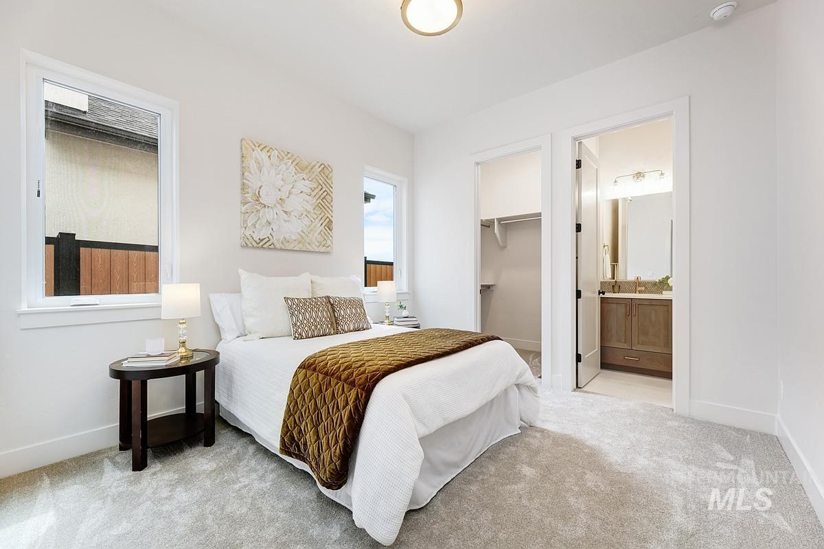 Bedroom featuring light carpet, a spacious closet, and ensuite bathroom
