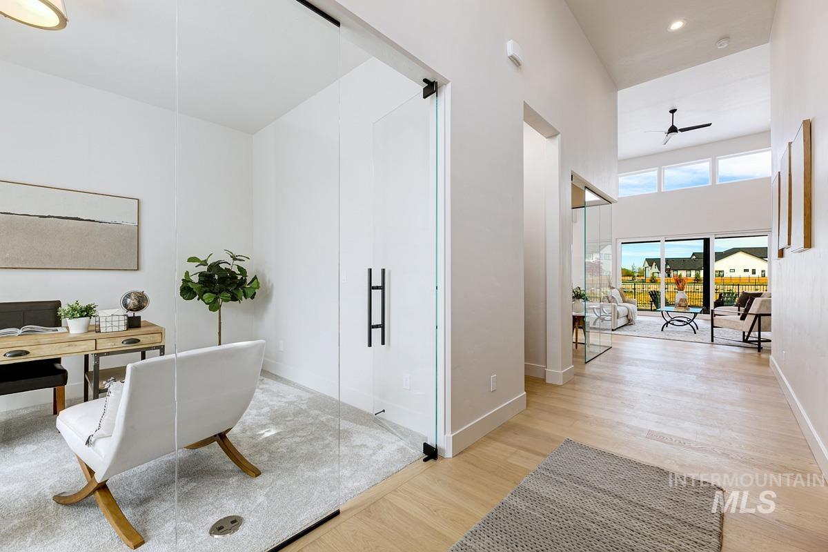 Home office featuring a ceiling fan, light wood-type flooring, and a towering ceiling
