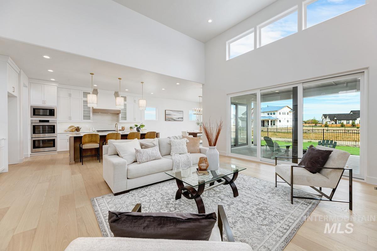 Living room featuring light wood-style floors, a high ceiling, and recessed lighting