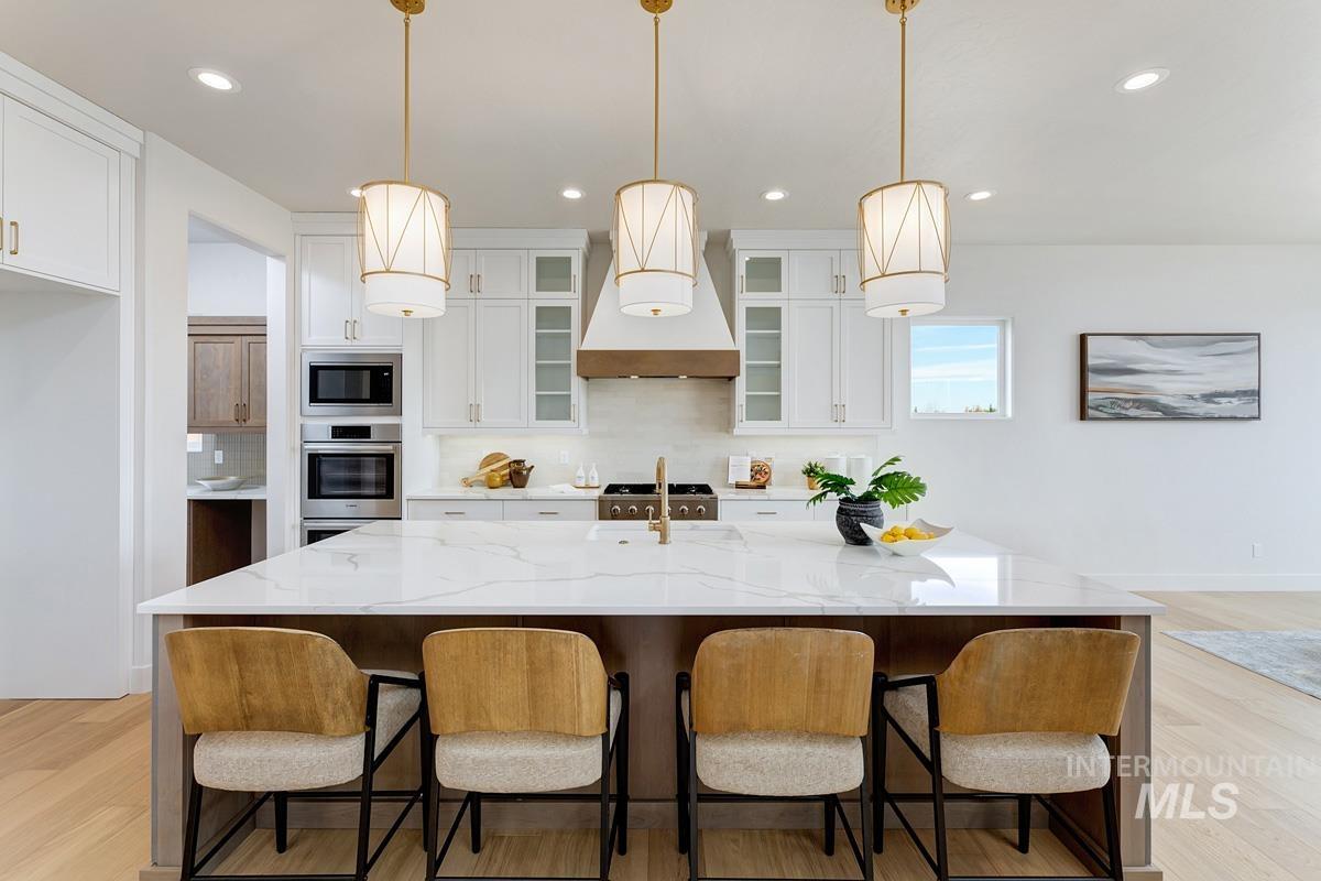 Kitchen with light wood-style floors, white cabinets, glass insert cabinets, tasteful backsplash, and recessed lighting