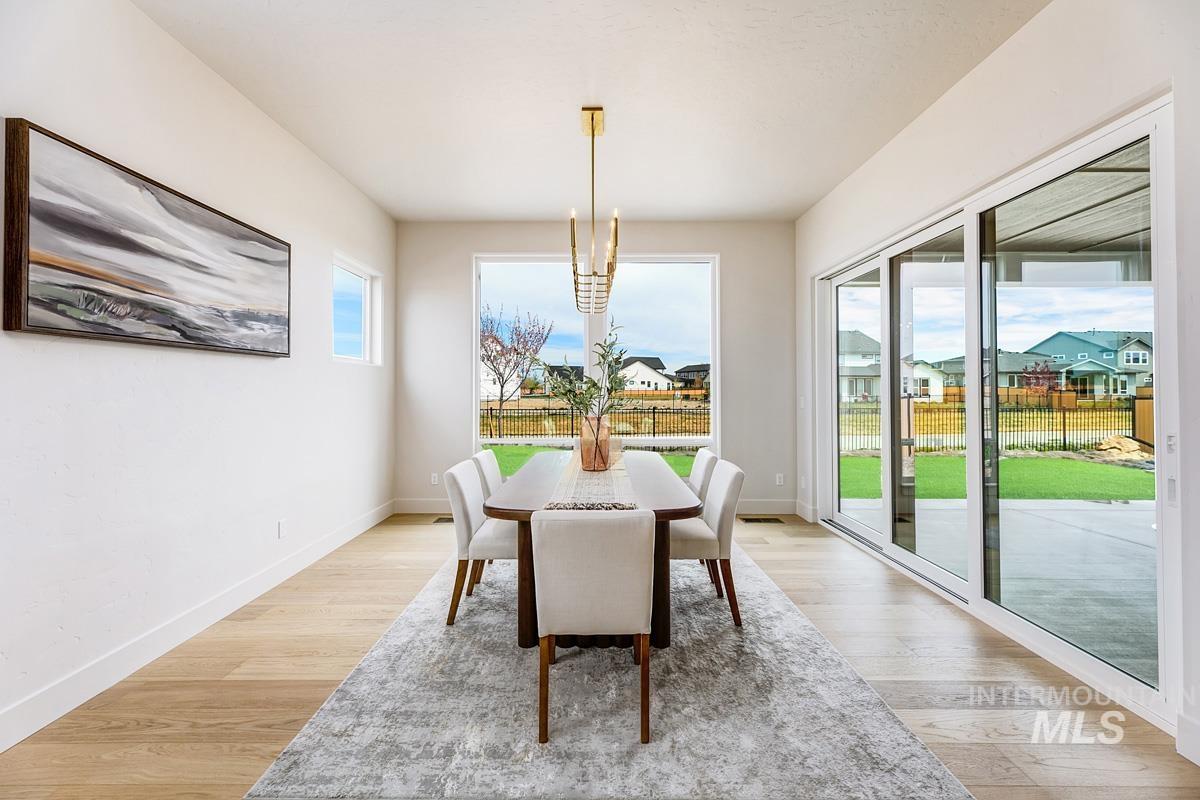 Dining space with light wood-type flooring, a chandelier, and a residential view