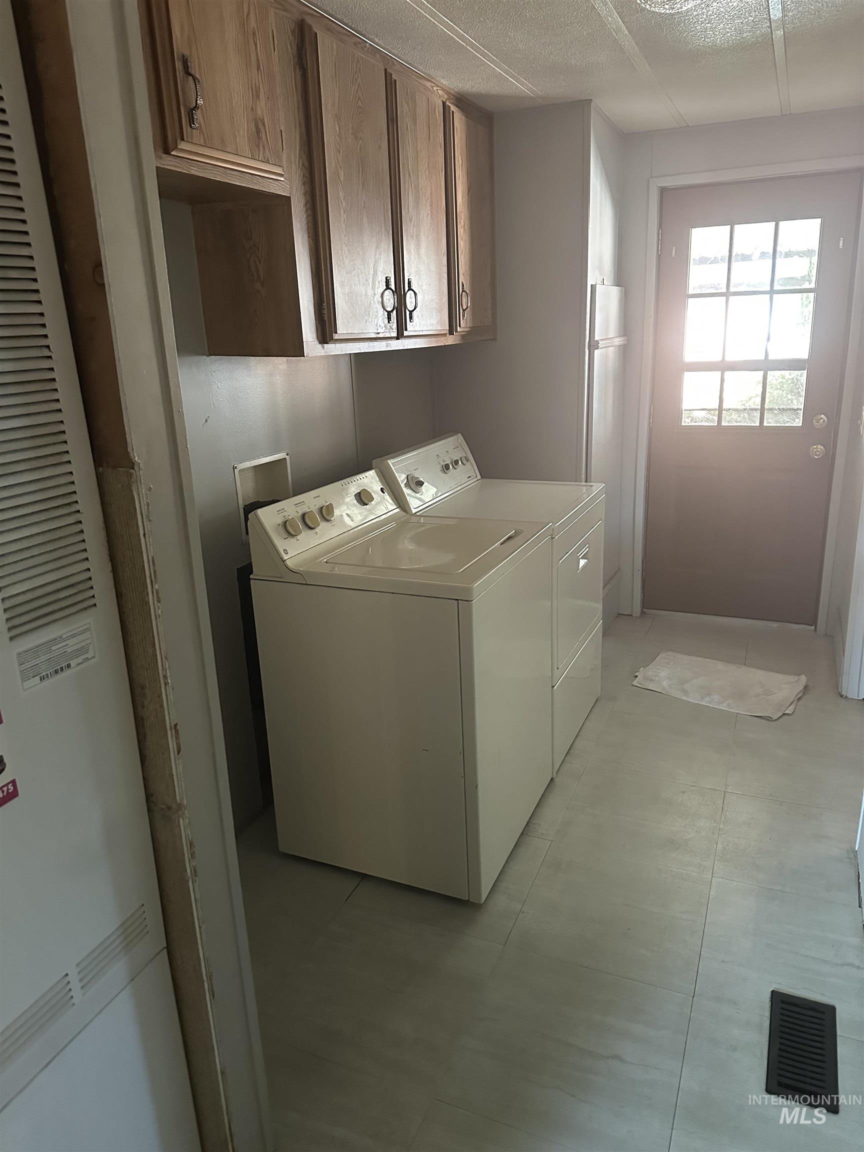 Laundry area featuring cabinet space, washing machine and clothes dryer, and a heating unit