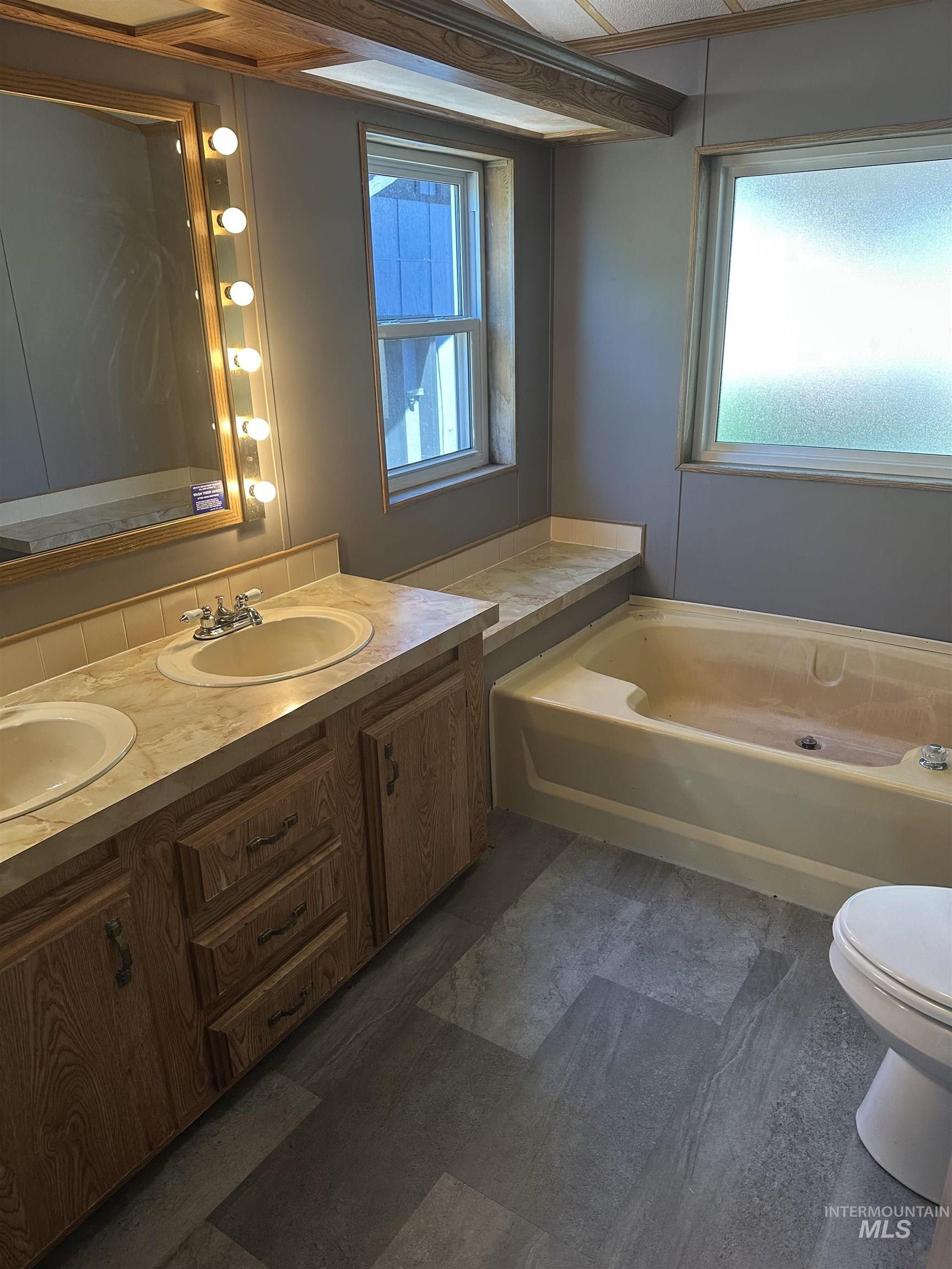 Full bath with a garden tub, double vanity, and plenty of natural light