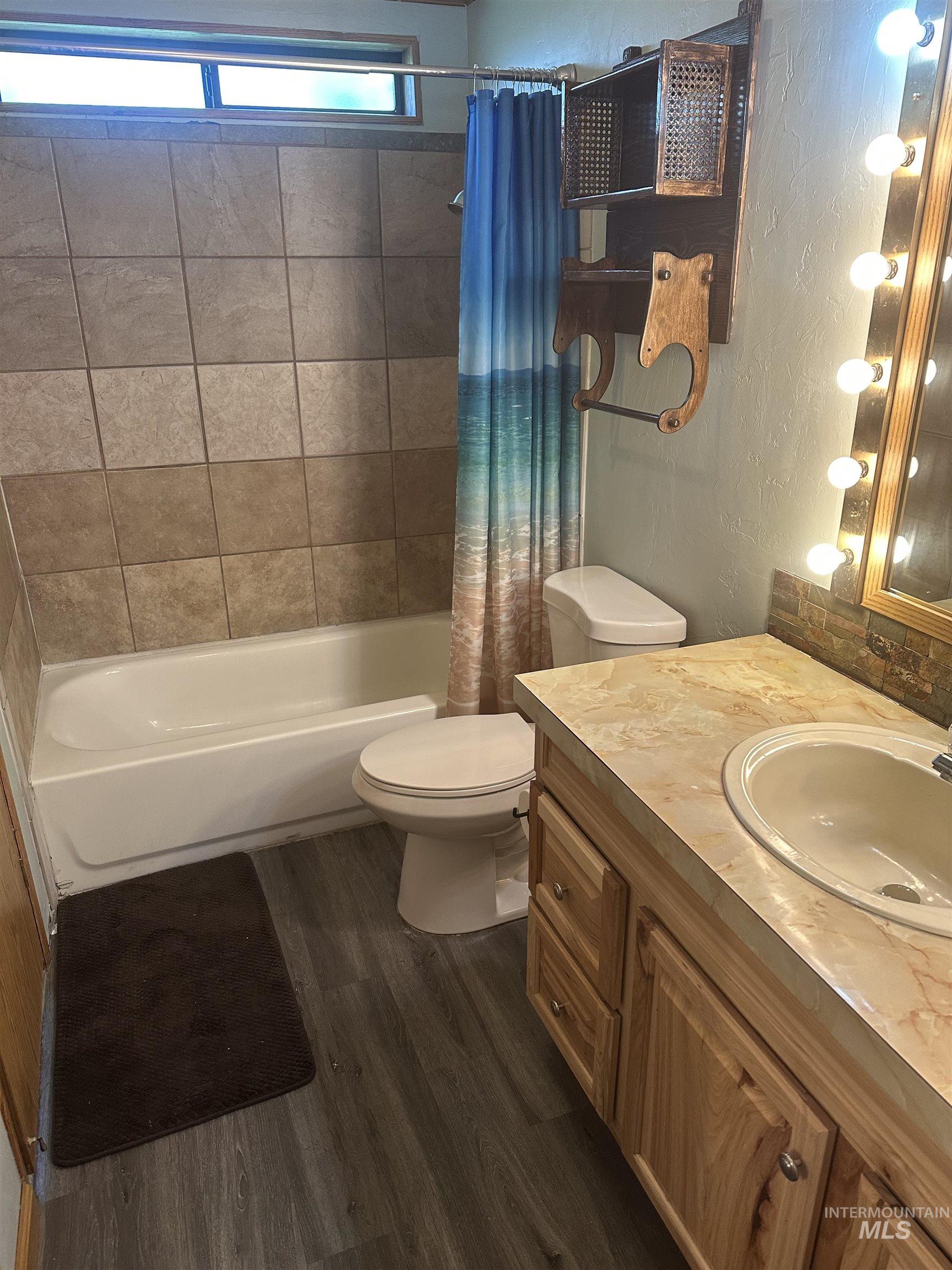 Full bathroom with vanity, wood finished floors, and shower / bath combo with shower curtain