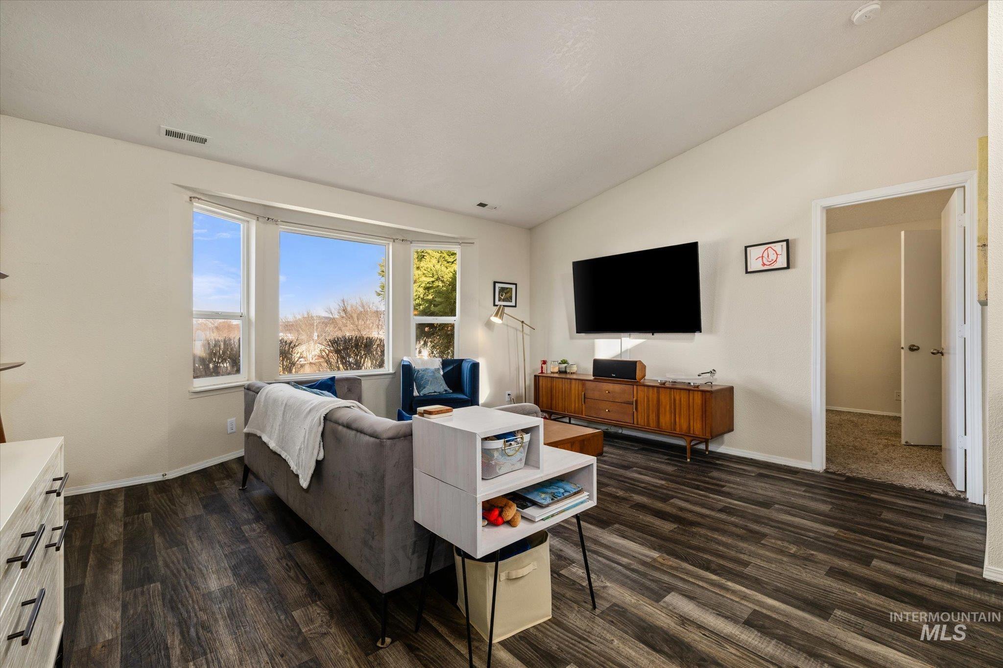 Living area featuring vaulted ceiling and dark wood finished floors