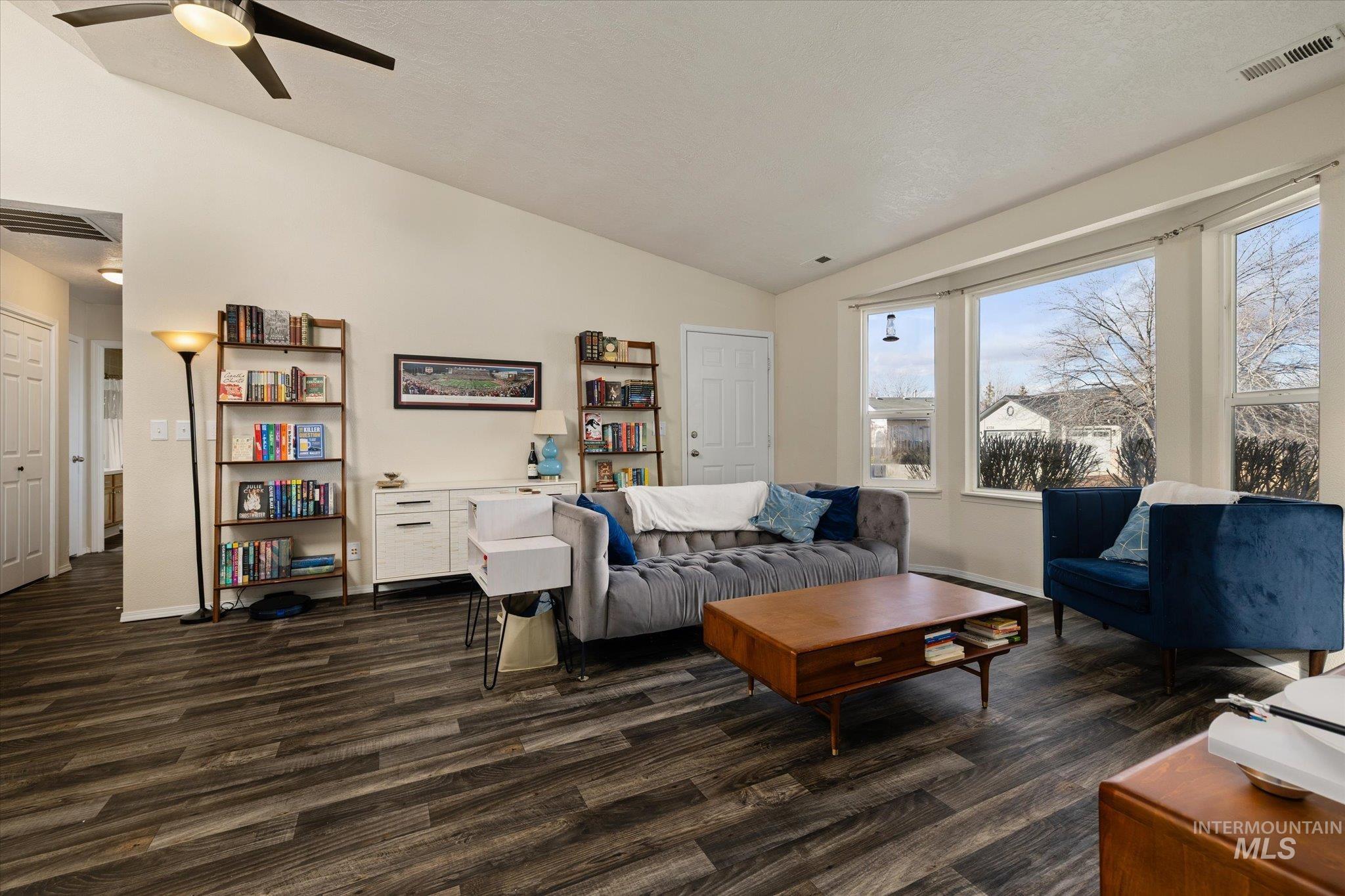Living area with vaulted ceiling, dark wood finished floors, and ceiling fan