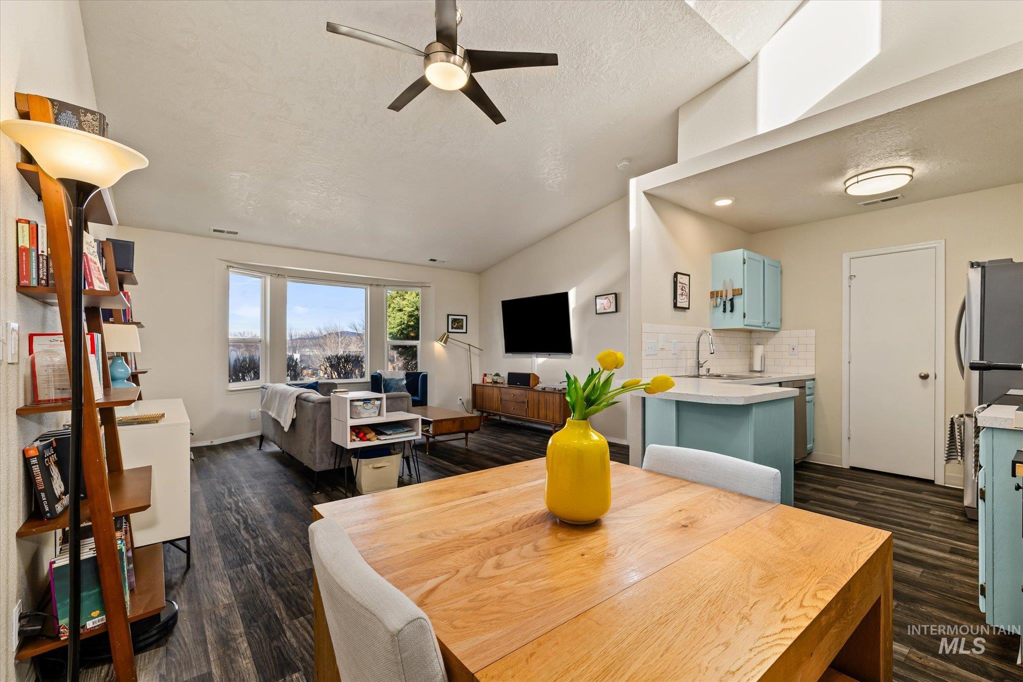 Dining room featuring ceiling fan, a textured ceiling, dark wood-style floors, and vaulted ceiling