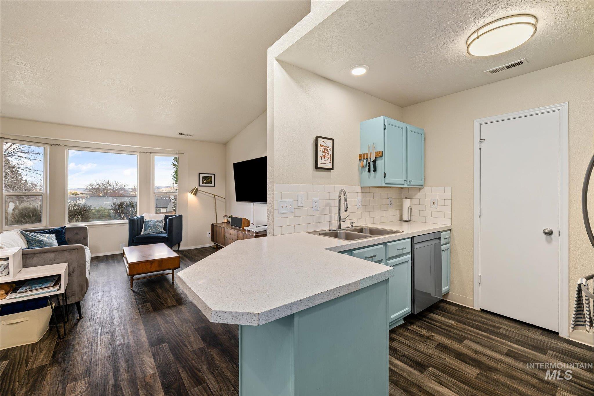 Kitchen featuring a peninsula, light countertops, backsplash, open floor plan, and lofted ceiling