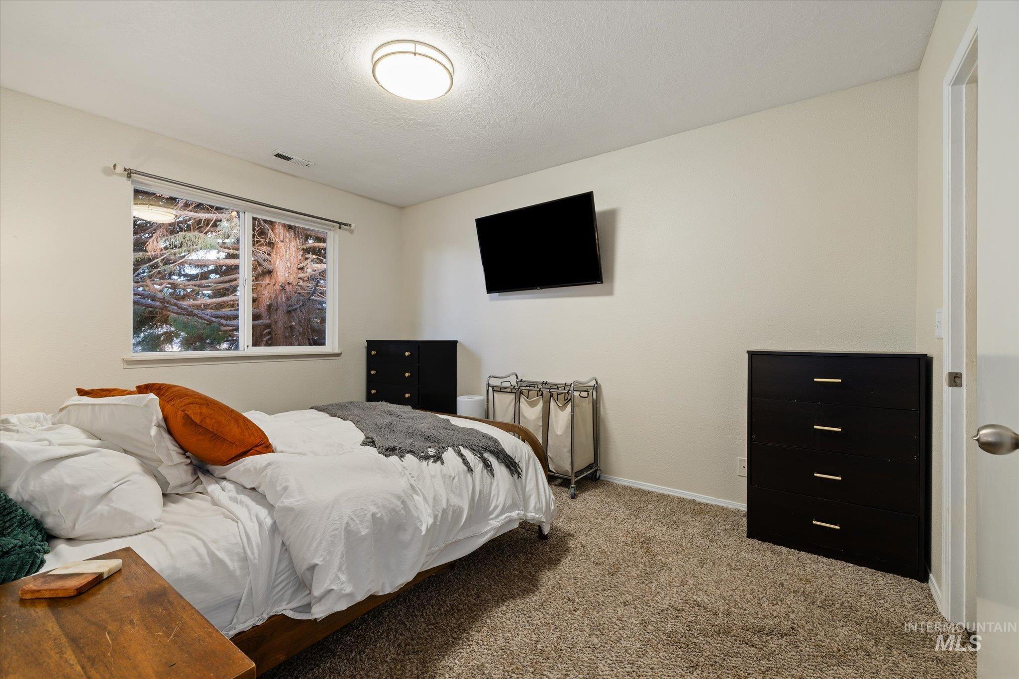 Carpeted bedroom featuring a textured ceiling and baseboards