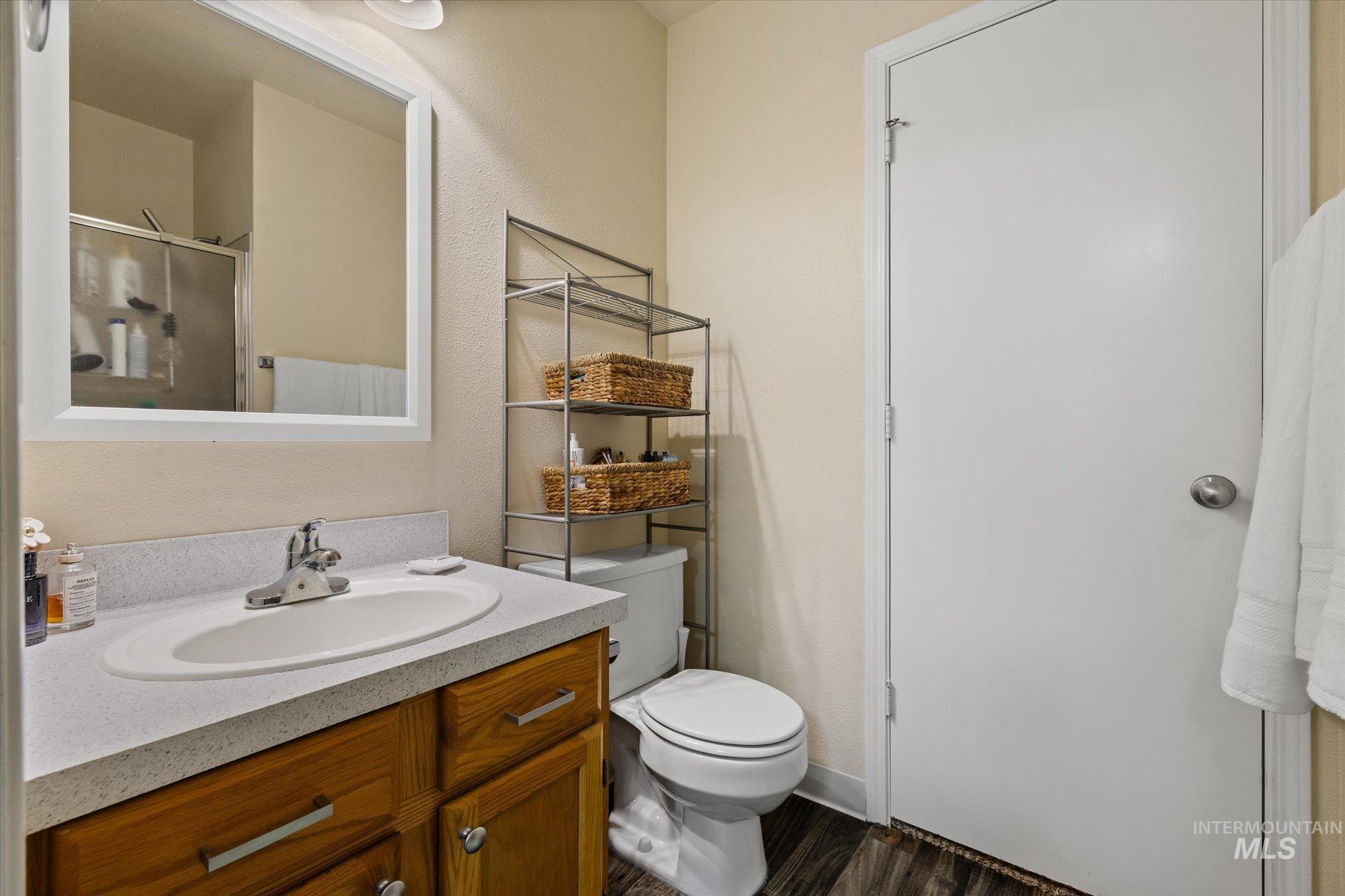 Bathroom featuring vanity, a shower with door, and dark wood-type flooring