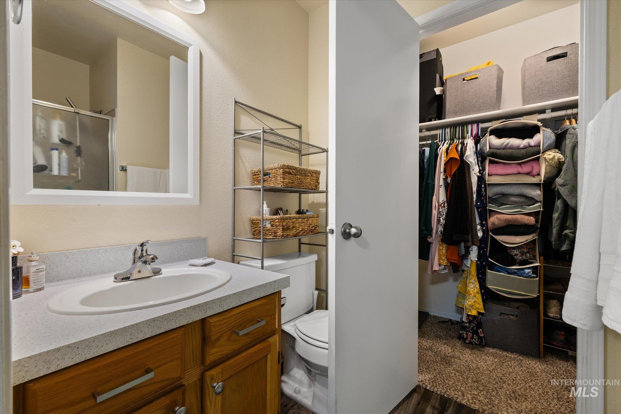 Full bathroom with vanity, a shower stall, a textured wall, and a spacious closet