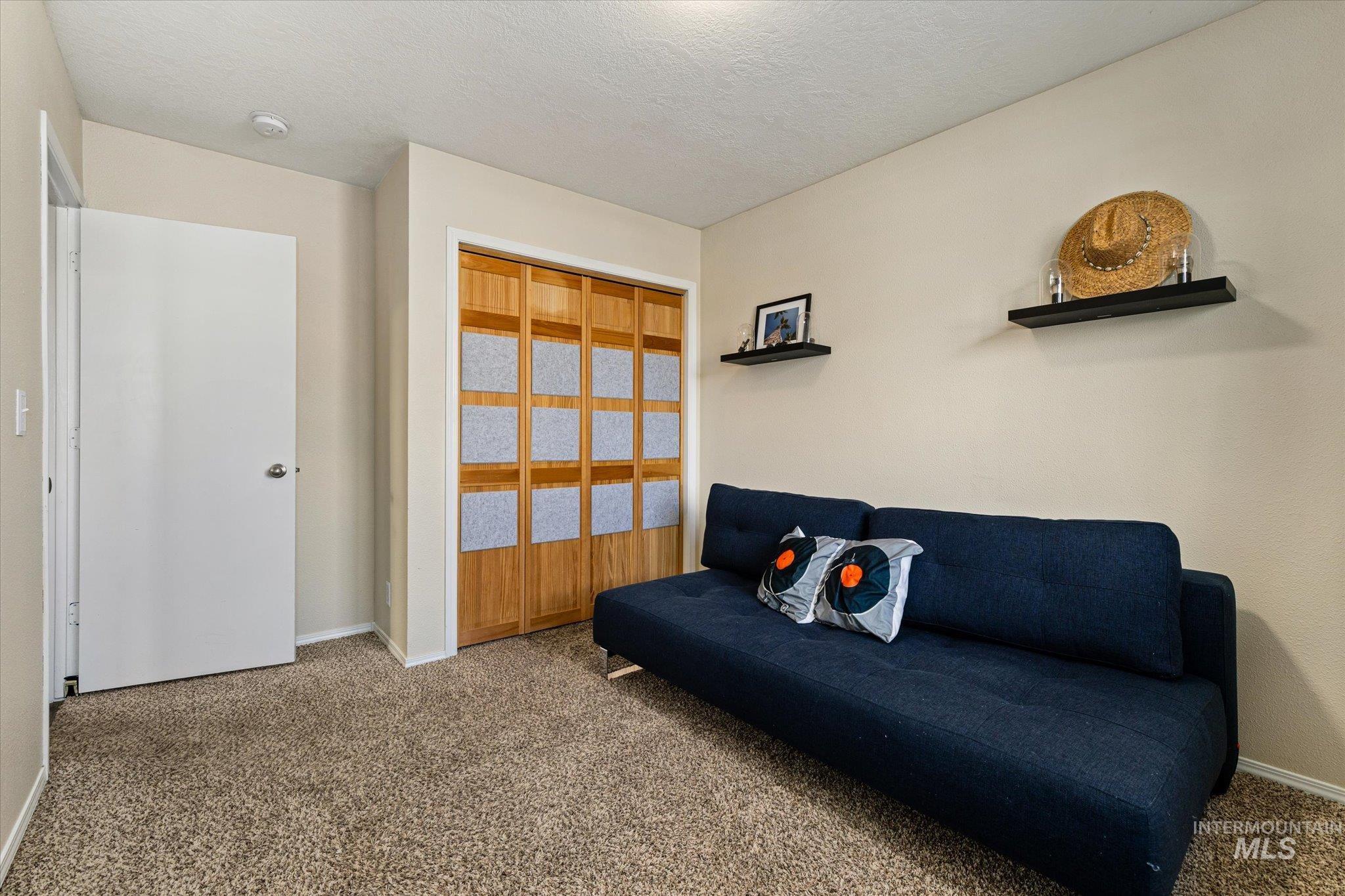 Living area featuring carpet and a textured ceiling