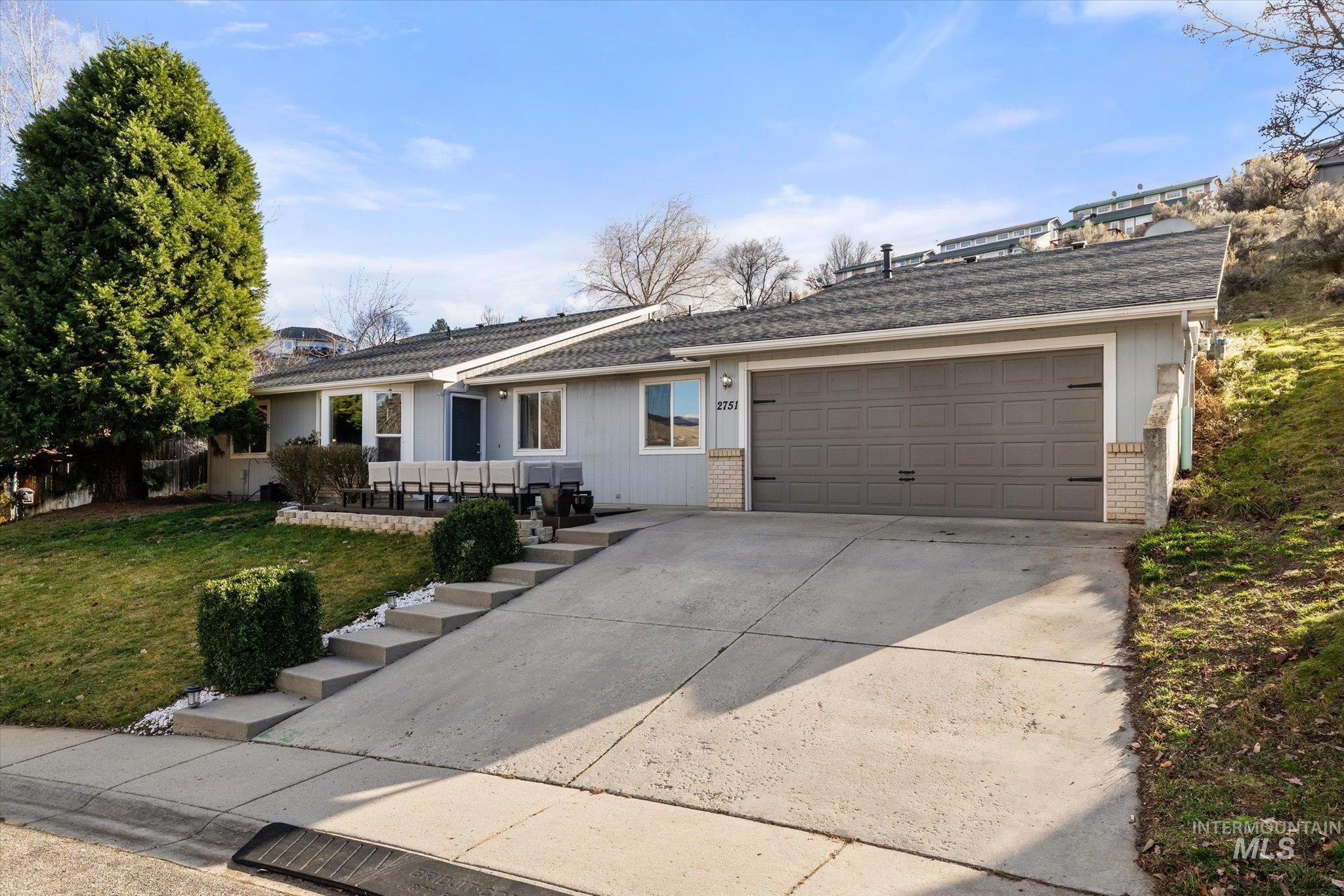 Ranch-style house with concrete driveway, a front lawn, brick siding, an attached garage, and roof with shingles