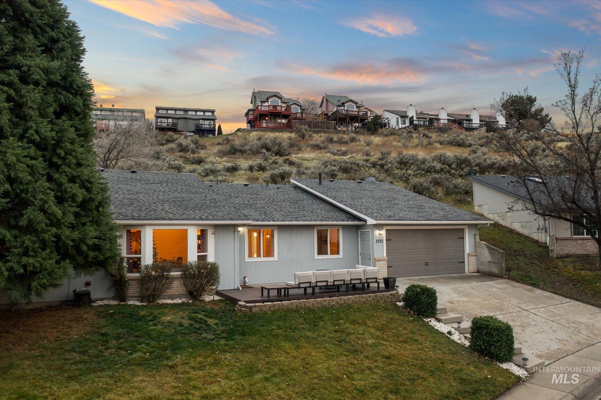 Ranch-style home with roof with shingles, concrete driveway, an attached garage, and a patio area