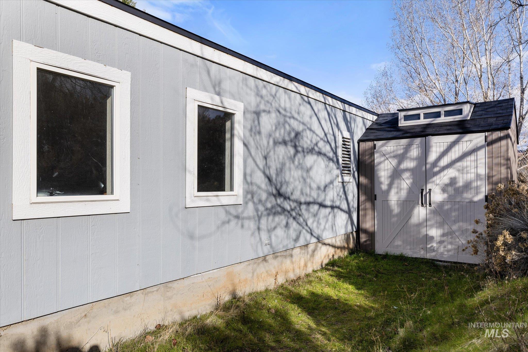 View of side of property featuring a storage shed and a yard