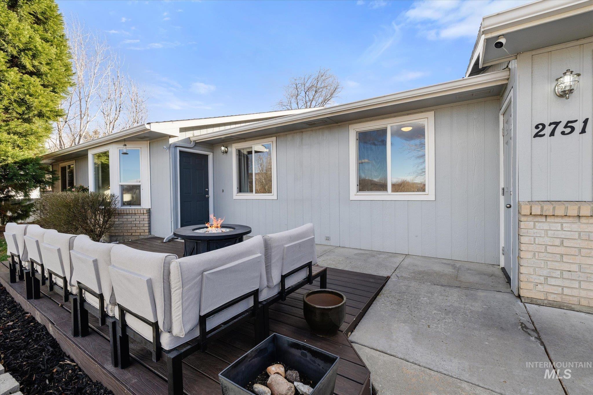 Front of house featuring an outdoor living space with a fire pit, brick siding, a patio, and a wooden deck