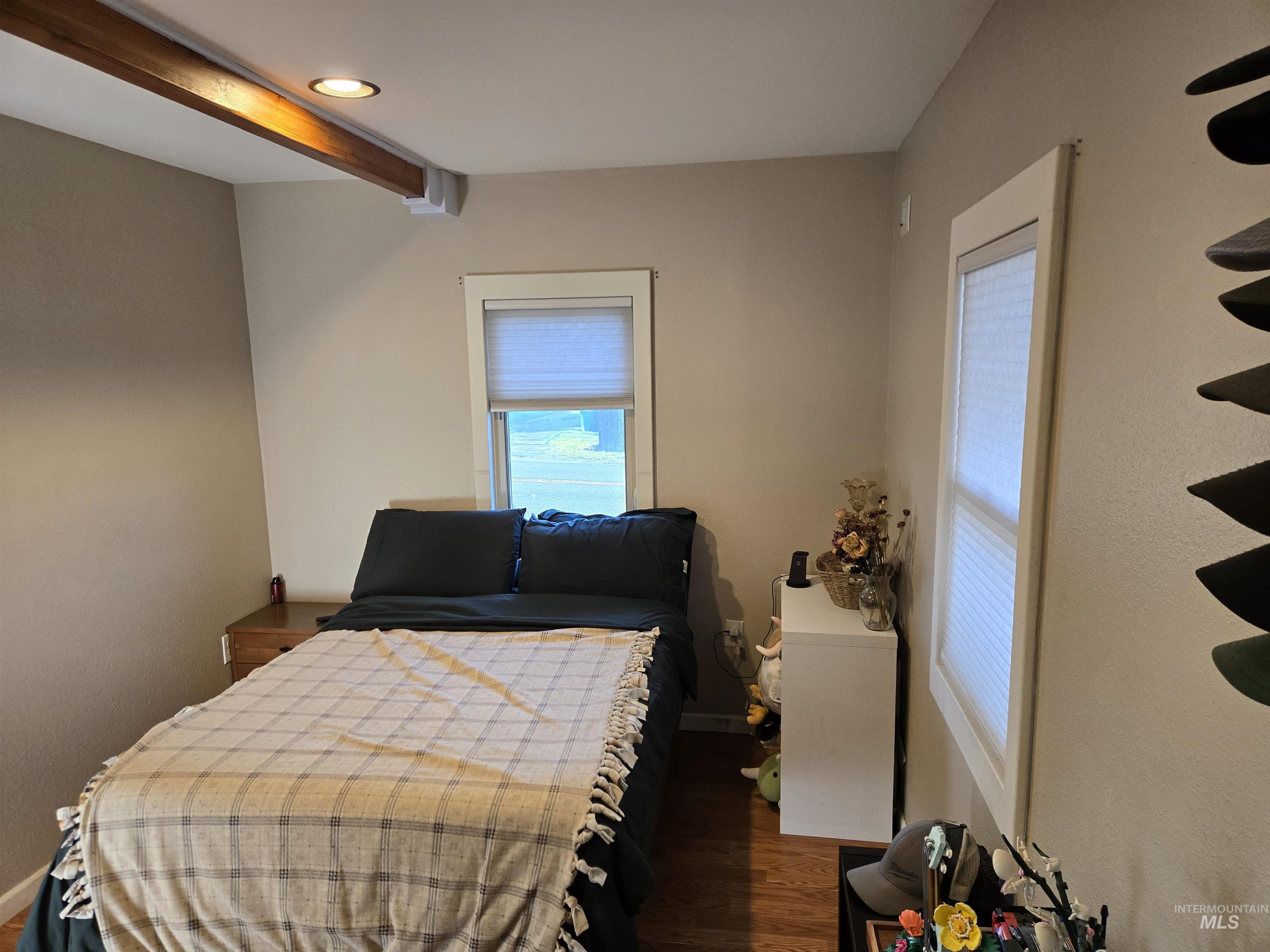 Bedroom featuring dark wood finished floors and beamed ceiling