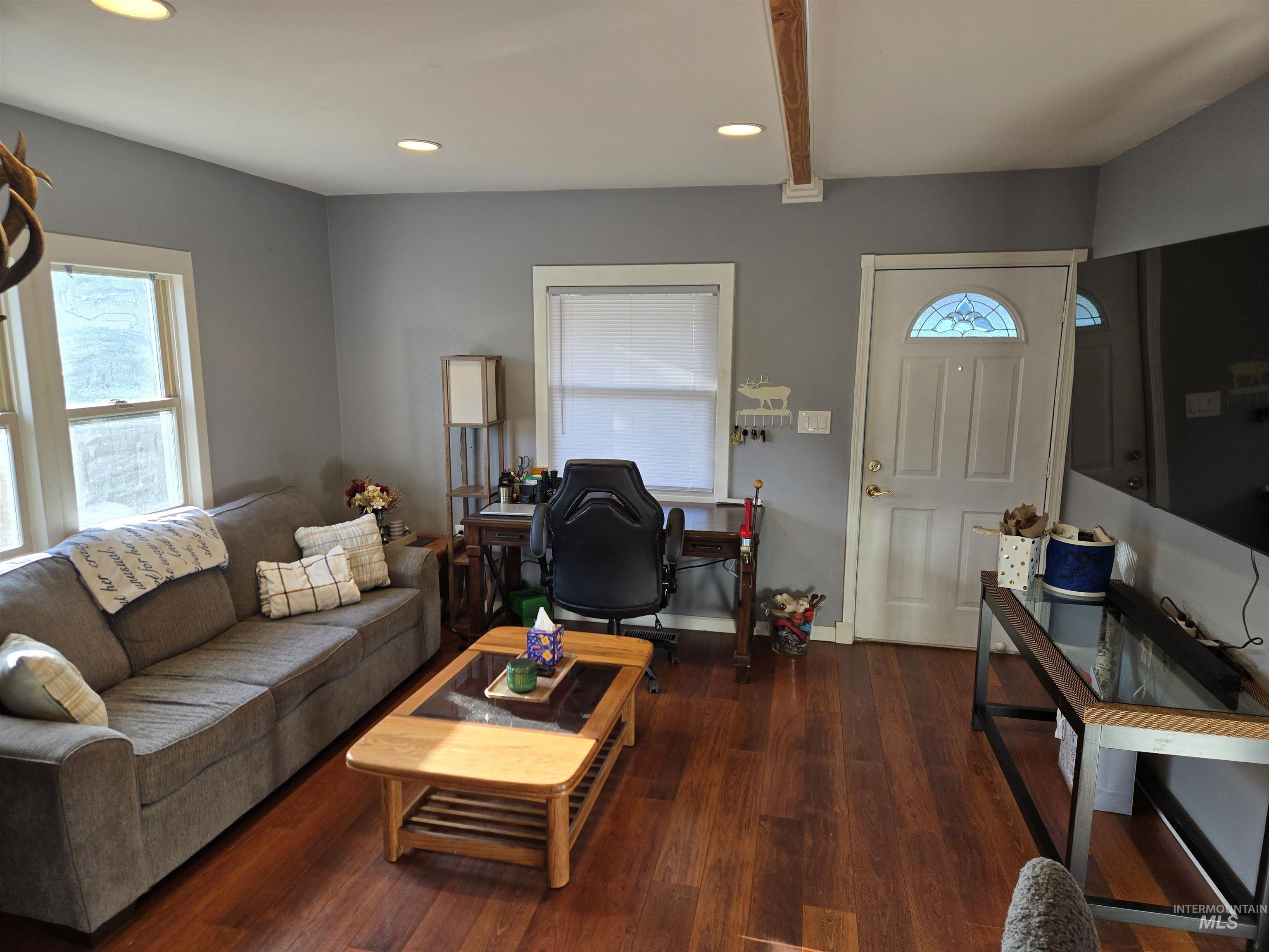 Living room featuring recessed lighting, dark wood-type flooring, healthy amount of natural light, and beamed ceiling