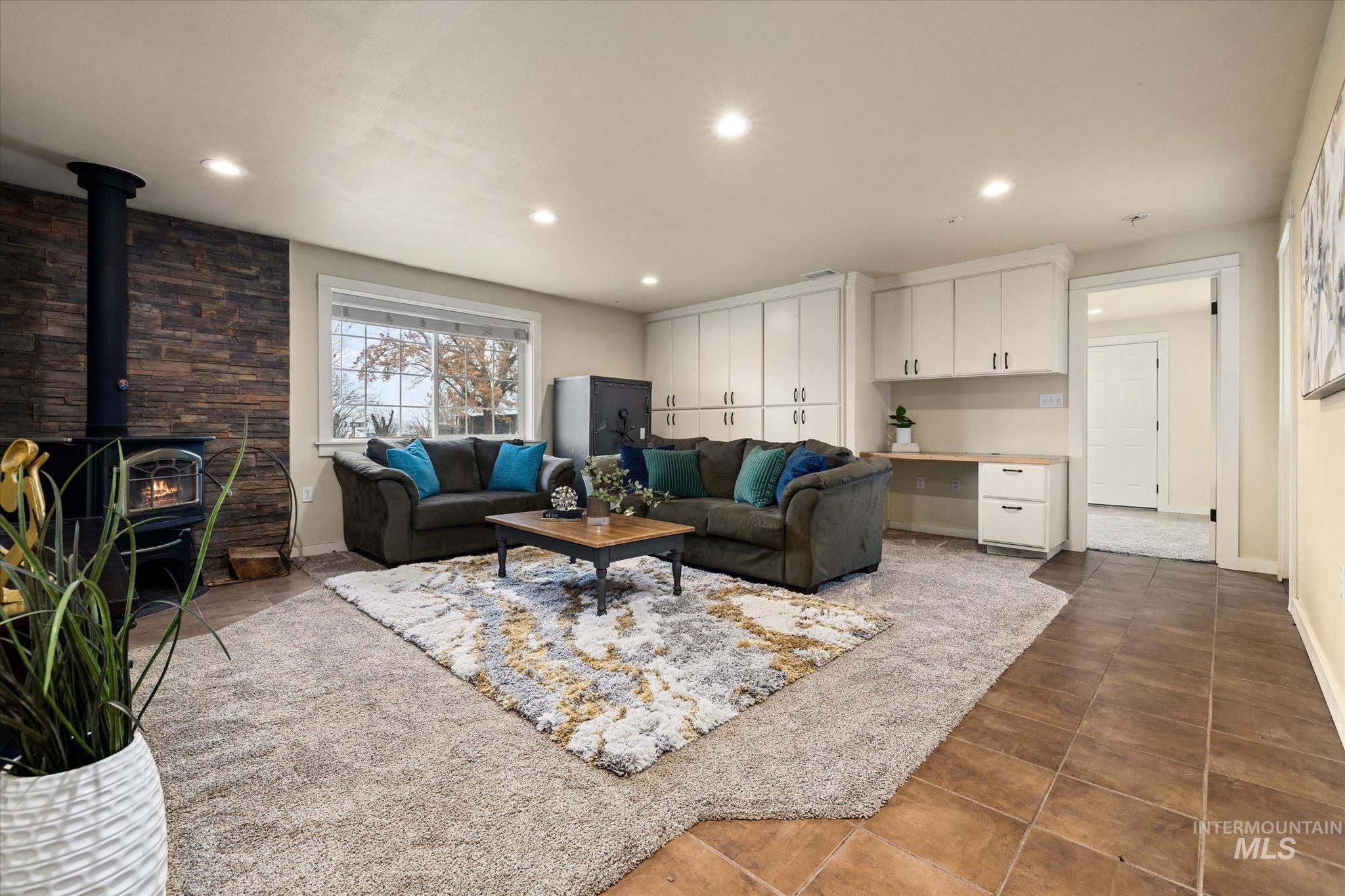 Tiled living room with built in desk, a wood stove, and recessed lighting