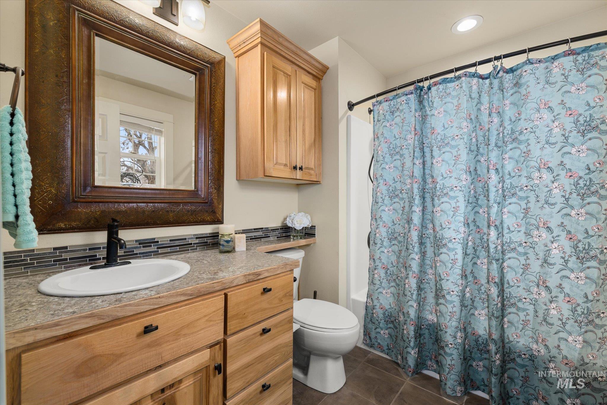 Full bath featuring vanity, shower / tub combo with curtain, dark tile patterned floors, and recessed lighting