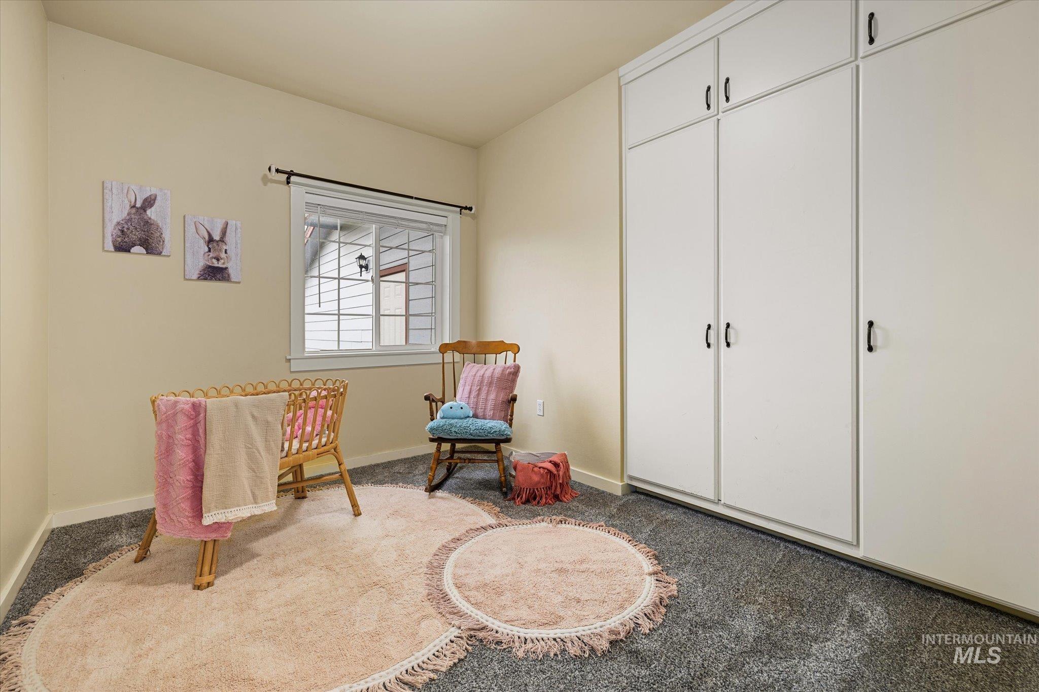 Living area featuring light colored carpet and baseboards