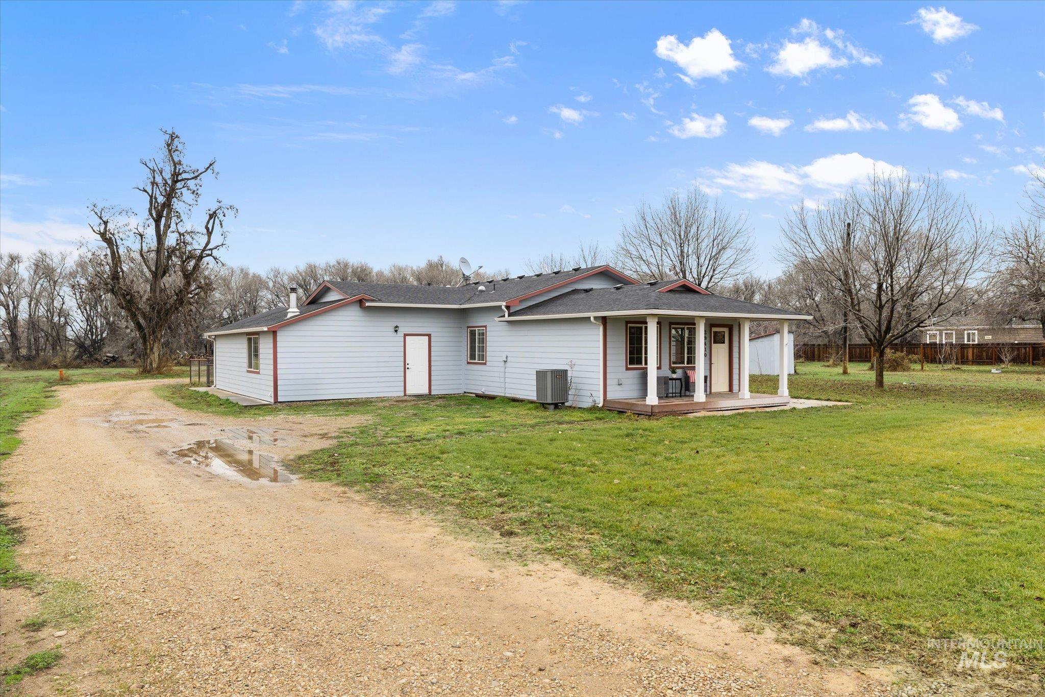 View of front of home featuring dirt driveway, a front yard, and roof with shingles